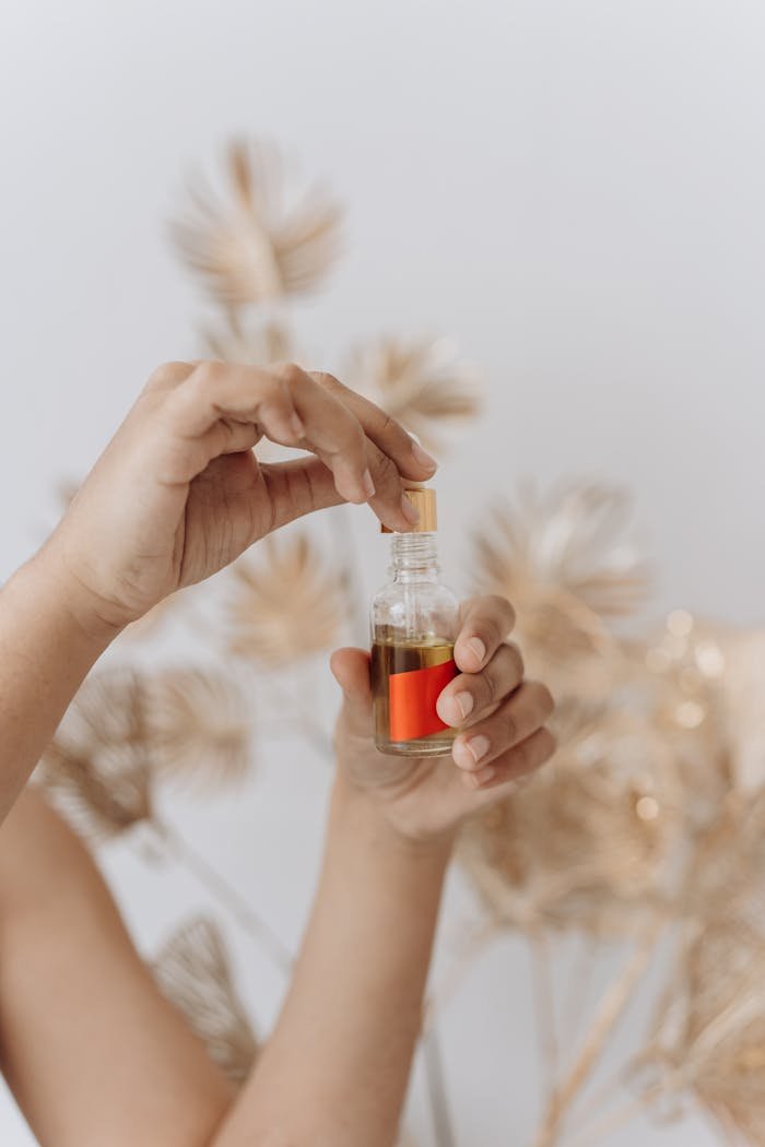 Close-up of hands with a pipette holding skincare oil bottle against a soft background.